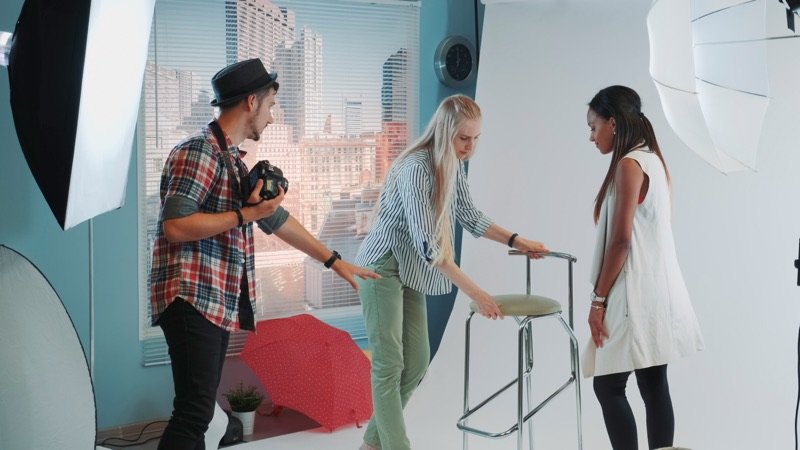 A creative team directing a model during a studio photoshoot