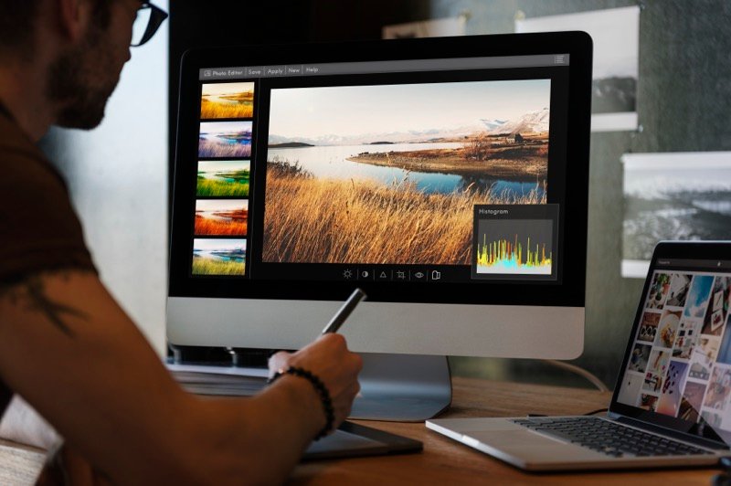 A photographer editing images on a monitor with a pen tablet